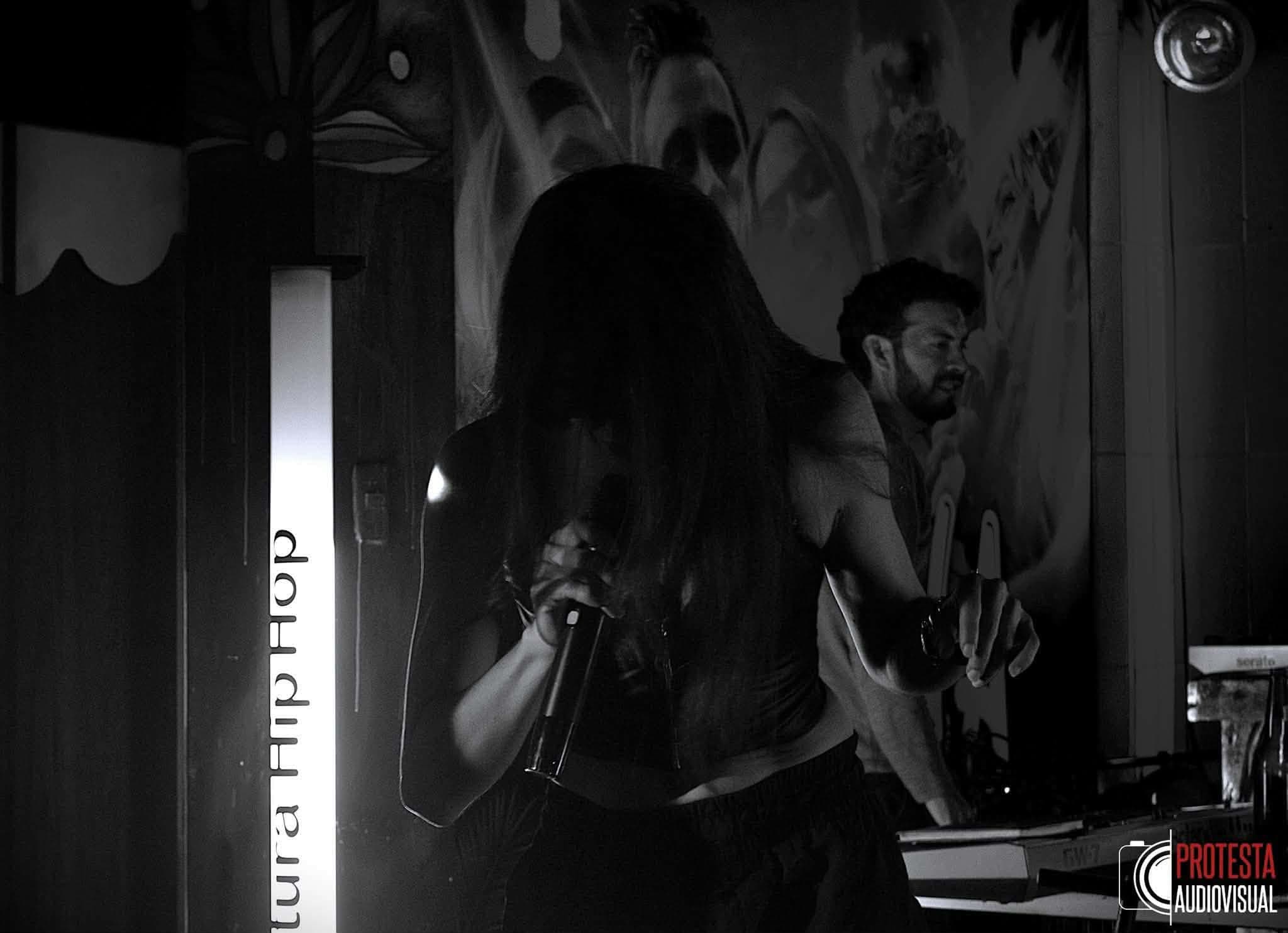 Andrea Vaca con micrófono en un evento de cultura hip hop, en blanco y negro