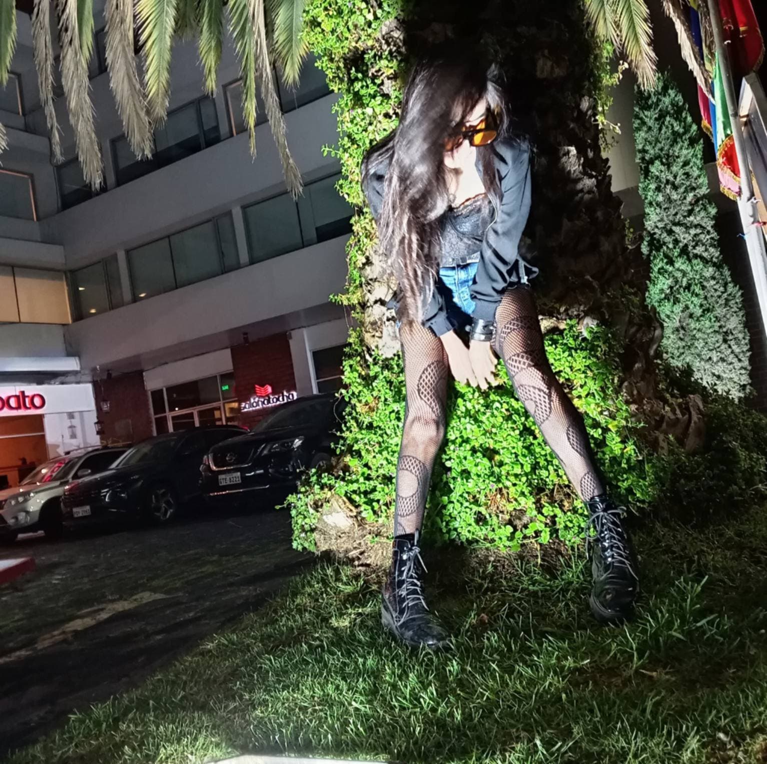 Andrea Vaca posando junto a una palmera de noche